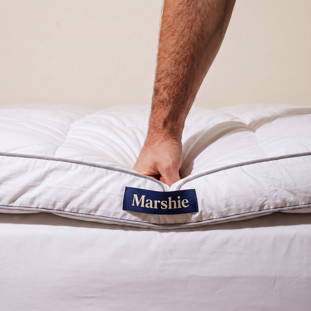 A hand pressing deep into the 10 cm Marshie Topper above the navy Marshie label